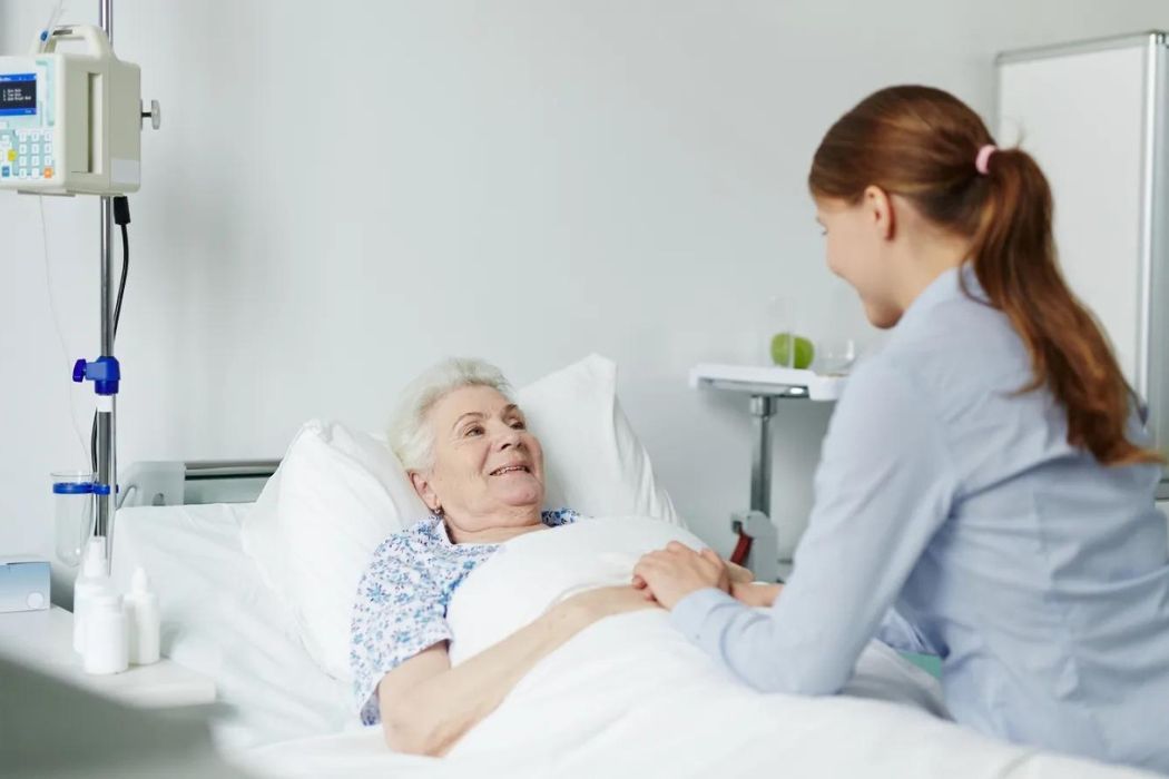 A nurse with an elderly woman, providing care during her post op recovery.