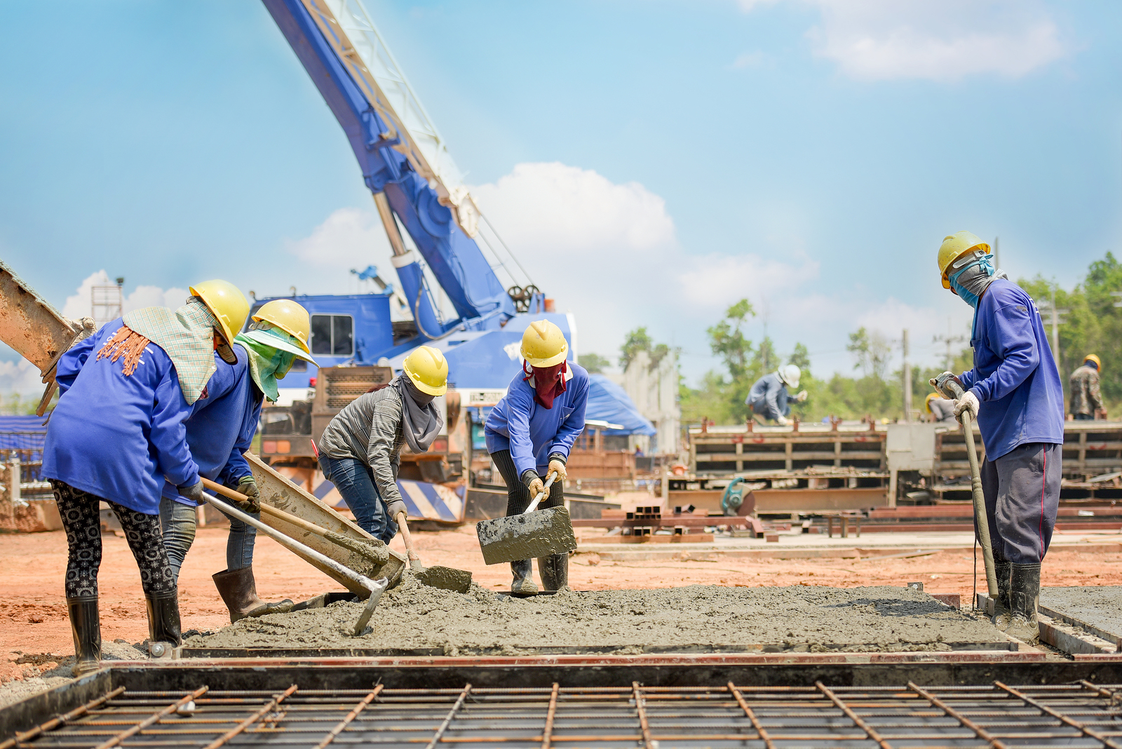 A group of construction workers in safety gear are actively working on a construction site, surrounded by equipment and materials.