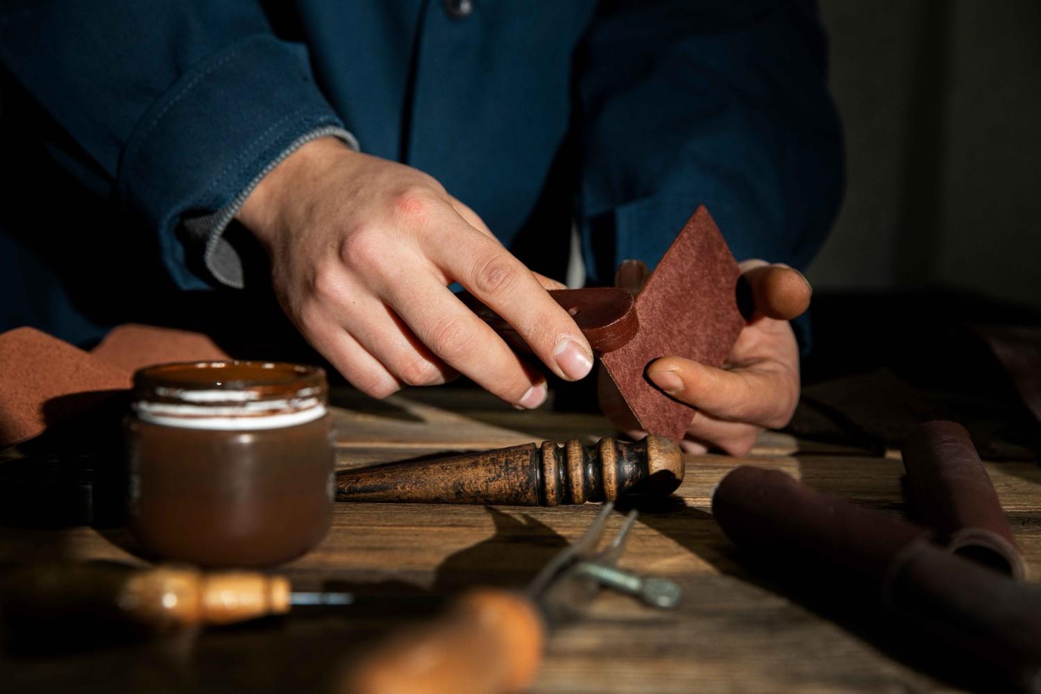 A man skillfully working on a leather piece with various tools, showcasing his expertise in DIY leather projects.