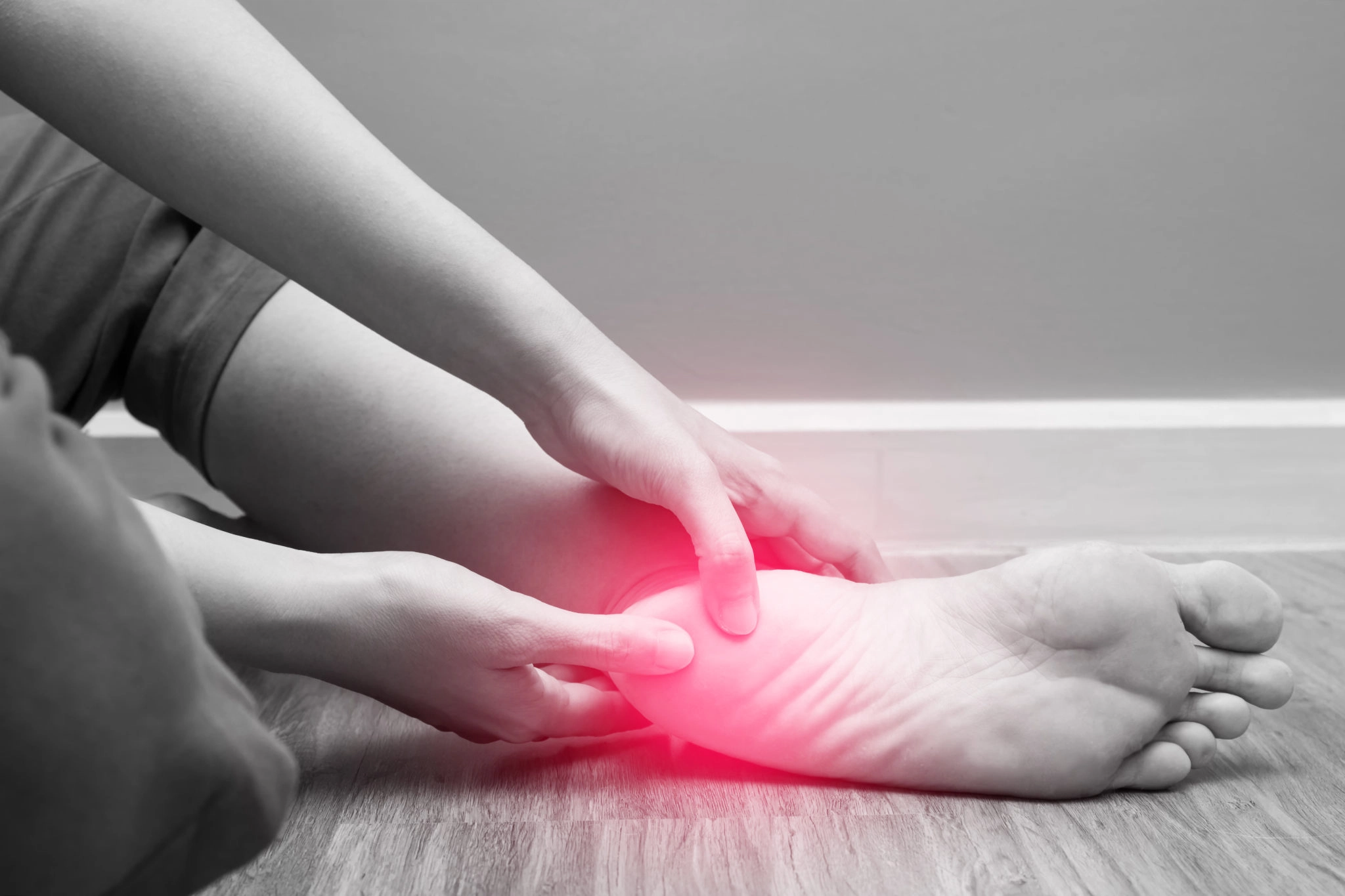 A person suffering from flat feet, rubbing his feet while in pain